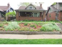 Charming brick bungalow featuring a beautifully landscaped front yard and cozy front porch at 832 S Gilpin St, Denver, CO 80209