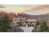 Spectacular stone home with a tiled roof, surrounded by towering red rock formations at 3755 N Rampart Range Rd, Littleton, CO 80125