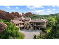 Stunning exterior elevation of luxury home with stone facade, tile roof and circular driveway at 3755 N Rampart Range Rd, Littleton, CO 80125