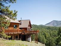 Wood cabin featuring a spacious deck with scenic views of the surrounding forest and mountains at 750 Cougar Dr, Boulder, CO 80302