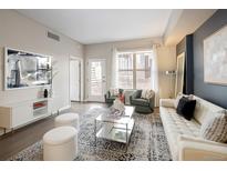 Bright living room boasts modern decor, city views from the window, and hardwood floors at 1975 N Grant St # 617, Denver, CO 80203