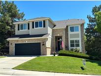 Charming two-story home with a manicured lawn, brick accents, and attached two-car garage at 8114 Briar Ridge Dr, Castle Pines, CO 80108