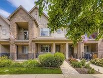 Charming townhome with a brick facade, covered porch, iron railing, and beautiful landscaping at 600 E Dry Creek Pl, Littleton, CO 80122