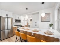 Bright eat-in kitchen features stainless steel appliances and breakfast bar with stylish pendant lighting at 862 Pontiac St, Denver, CO 80220