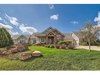 Charming exterior of home with beautiful landscaping, stone accents and lush green lawn under a cloudy blue sky at 8392 Niwot Meadow Farm Rd, Niwot, CO 80503