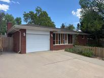 Charming single-story brick home featuring a two-car garage and a well-maintained front yard with mature trees at 1740 S Estes St, Lakewood, CO 80232