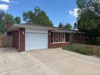 Charming brick ranch home featuring an attached garage and a well-maintained concrete driveway at 1740 S Estes St, Lakewood, CO 80232
