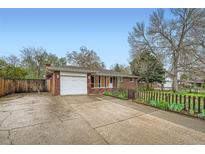 A single story brick home featuring an attached one car garage and a long, wide driveway at 1740 S Estes St, Lakewood, CO 80232