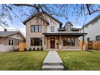 Beautiful two-story home with a brick facade, covered porch, and manicured lawn at 2056 S Ogden St, Denver, CO 80210