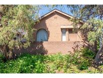 Charming brick house featuring unique arched window and lush landscaping at 1257 Quitman St, Denver, CO 80204