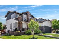 Charming two-story home with a manicured lawn, stone accents, and a covered front porch at 14110 Pastel Ln, Parker, CO 80134