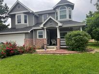 Charming two-story home with a landscaped yard and blooming red roses at 5491 S Youngfield W Ct, Littleton, CO 80127