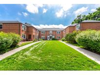 Attractive brick apartment building with well-manicured lawn and inviting entrance walkway under a cloudy blue sky at 2856 Jasmine St, Denver, CO 80207