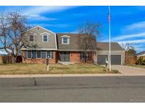 Charming two-story home with brick and gray siding, manicured lawn, and American flag on a sunny day at 4991 S Beeler. St, Greenwood Village, CO 80111
