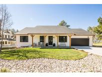 Charming single-story home featuring a well-manicured front yard and a welcoming covered porch with seating at 1288 Gambel Oaks Dr, Elizabeth, CO 80107