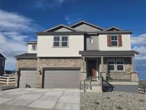 Charming two-story home with stone accents, covered porch, three-car garage, and manicured front yard at 1667 Fox Trotter Pt, Castle Rock, CO 80104