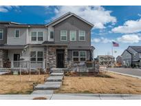 Charming townhouse with stone accents, inviting porch, and landscaped front yard on a sunny day at 688 N Bersshine Ct, Watkins, CO 80137