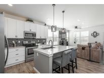 Bright kitchen features stainless steel appliances, center island with barstool seating, and an open-concept layout at 688 N Bersshine Ct, Watkins, CO 80137