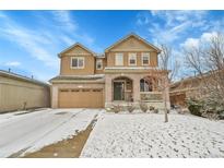 Charming two-story home with a brick facade, covered porch, and attached garage nestled in a winter landscape at 239 N Irvington St, Aurora, CO 80018