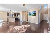 Sun-drenched open layout with hardwood floors leading from a modern kitchen to a cozy living space with a mounted TV at 21893 E Layton Dr, Aurora, CO 80015