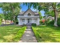 Charming two-story home boasts a welcoming front porch and well-manicured lawn with mature trees at 7011 Grandview Ave, Arvada, CO 80002