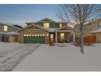 Two-story brick home with green accents and a snow-covered front yard at 6344 E 137Th Ave, Thornton, CO 80602