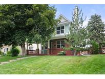 Charming two-story home featuring a well-maintained lawn, mature trees, and a welcoming front porch at 1544 S Elizabeth St, Denver, CO 80210