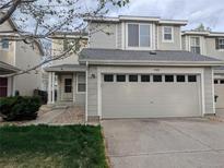 Charming two-story townhome showcasing a light gray exterior, a two-car garage, and manicured lawn at 9322 Jackson St, Thornton, CO 80229