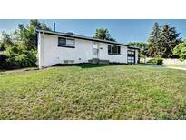 Charming single-story home featuring a well-maintained lawn and a classic white brick facade at 7704 Newland St, Arvada, CO 80003