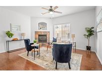 Bright living room features a fireplace, wood floors, ceiling fan, two chairs and a neutral color palette at 8603 E Dry Creek Rd # 214, Englewood, CO 80112