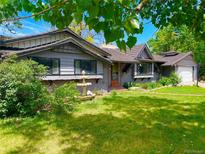 Charming one-story home featuring a lush front yard with a water fountain and mature trees at 6429 W 5Th Pl, Lakewood, CO 80226