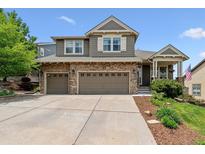 Charming two-story home with stone accents, neutral siding, and a three-car garage on a sunny day at 1575 Ridgetrail Ct, Castle Rock, CO 80104