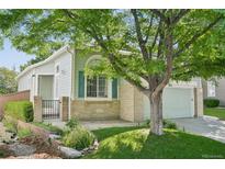 Charming home with a well-manicured lawn and mature tree providing shade in the front yard at 10231 Spotted Owl Ave, Highlands Ranch, CO 80129