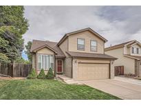 Charming two-story home with a well-manicured lawn and a two-car garage with brick and tan siding at 2789 Decatur Dr, Broomfield, CO 80020