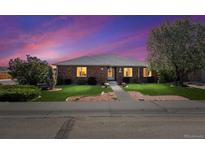 Charming brick home featuring a well-maintained lawn and walkway leading to the front door, set against a vibrant sunset sky at 640 N 15Th Ave, Brighton, CO 80601