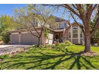 Charming two-story home featuring a well-manicured lawn, mature trees, and a welcoming front porch at 4875 E 117Th Dr, Thornton, CO 80233