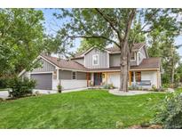 Beautiful two-story house with gray siding, brown roof, and a large tree in the front yard at 5152 W Maplewood Pl, Littleton, CO 80123