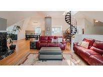 Cozy living room with a red leather sofa, hardwood floors, and views of the unique spiral staircase at 1165 N Pennsylvania St # 3B, Denver, CO 80203