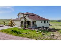 Charming two-story home features a stone-accented porch, attached garage, and lush green landscaping with a sprawling lawn at 28340 Dylon Cir, Elizabeth, CO 80107