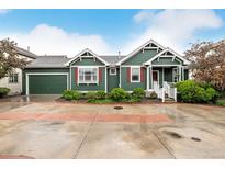 Charming green home with red shutters, a well-maintained lawn and an attached two-car garage at 13263 Niwot Trl, Broomfield, CO 80020