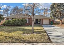 Charming brick home featuring a well-manicured lawn and a long, paved driveway leading to an attached garage at 2675 N Saint Paul St, Denver, CO 80205