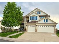 Charming two-story home featuring a three car garage, blue shutters, and professionally landscaped yard at 22962 Briar Leaf Ave, Parker, CO 80138