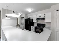 Bright kitchen features black appliances, white cabinets, breakfast bar and stacked washer/dryer at 4899 S Dudley St # 15B, Littleton, CO 80123