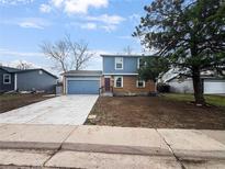 Split-level home with brick and blue siding, a concrete driveway, attached garage, and freshly laid lawn at 4777 S Olathe St, Aurora, CO 80015