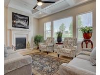 Bright living room featuring a fireplace, coffered ceiling, and natural light from large windows at 23636 E Del Norte Pl, Aurora, CO 80016