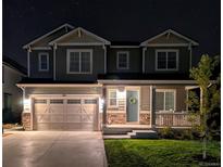 Charming two-story home featuring a spacious garage, inviting porch, and well-manicured lawn under a starry night sky at 821 Boulder Peak Ave, Erie, CO 80516