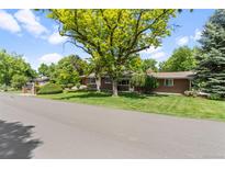Charming brick home featuring mature trees, lush lawn, and lovely landscaping at 2520 Eldridge Cir, Golden, CO 80401