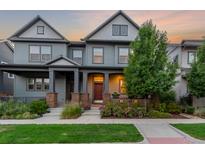 Charming gray home boasts a meticulously landscaped front yard with colorful flowers and a welcoming covered porch at 5735 Boston St, Denver, CO 80238