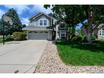 Charming two-story home with a well-maintained lawn, large tree and a driveway with a basketball hoop at 1387 Mcintosh Ave, Broomfield, CO 80020