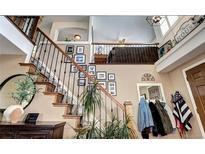 Charming entryway with wood stairs, iron railing, and decorative wall art leading to upper level at 4907 Fenwood Dr, Highlands Ranch, CO 80130